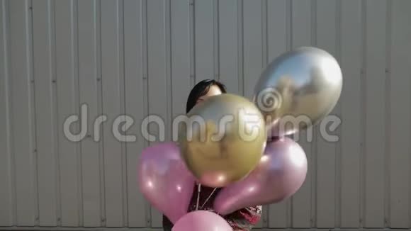 穿着漂亮的女人白天在室外拿着氦气气球视频的预览图