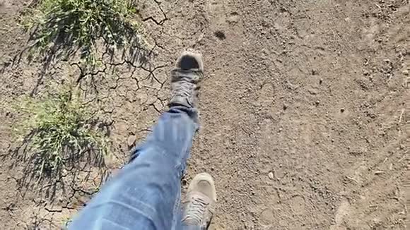 一个穿牛仔裤的人的腿在一条尘土飞扬的道路上缓慢地行走视频的预览图