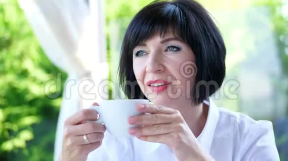 愉快微笑的肖像快乐美丽的真实40岁的乌克兰女人喝咖啡茶的女人视频的预览图