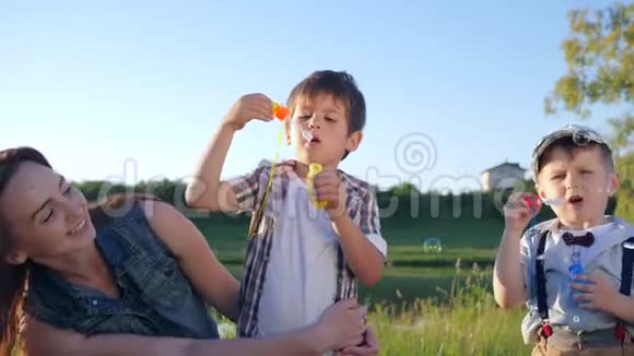 孩子们的关系可爱的小男孩和十几岁的女孩在草地上吹肥皂泡视频的预览图
