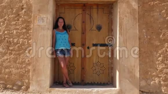 年轻女子站在背景门和岩石墙上视频的预览图