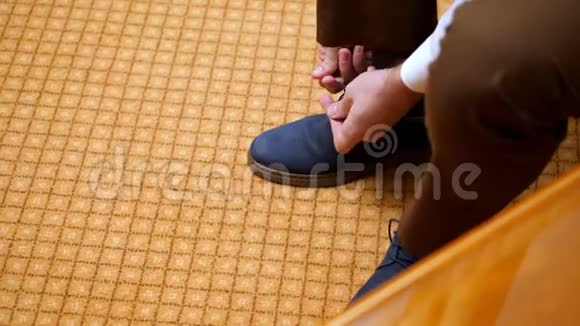 近距离看男人的手系鞋带这名男子正穿上他时髦的蓝色绒面皮鞋背景是地毯新郎视频的预览图