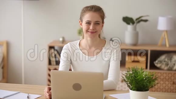 戴手提电脑的微笑女孩在家工作视频的预览图