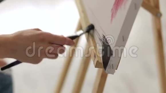 艺术家女孩的特写在画布的角落画黑色的颜料视频的预览图