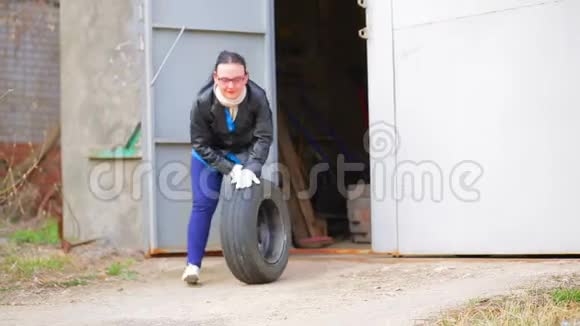 一个女人正在从车库里滚出一个带圆盘的轮胎视频的预览图