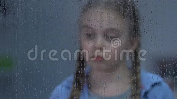 心烦意乱的女孩看着窗外的雨忍受着孤独等待着父母视频的预览图
