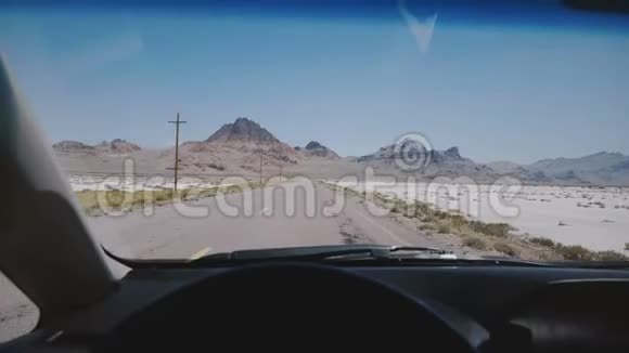 汽车行驶在史诗般的白色盐湖沙漠道路上朝着山脉和晴朗的蓝天地平线在美国犹他州邦纳维尔视频的预览图