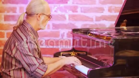 男子音乐家弹钢琴他穿着格子衬衫戴着眼镜戴着头发灰白视频的预览图