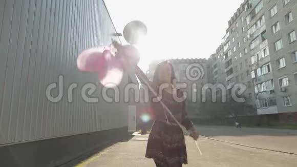 穿着漂亮的女人白天在室外拿着氦气气球视频的预览图