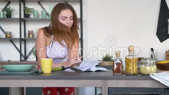 有趣的姜女在早上烹饪过程中阅读烹饪书在现代厨房跳舞视频的预览图
