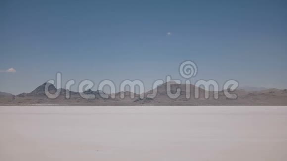 在犹他州令人难以置信的邦尼维尔盐湖沙漠中用相机驾驶的黑色小型货车的侧面拍摄视频的预览图