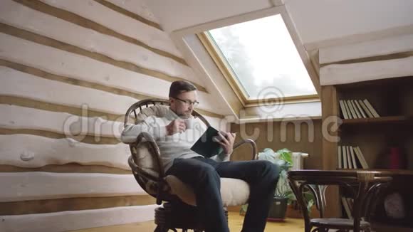 戴眼镜的大胡子聪明人在阁楼上看书喝咖啡视频的预览图