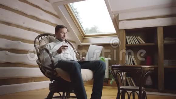 成年男子在椅子上用电脑喝酒视频的预览图