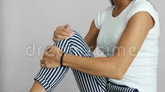 女子在康复中心揉揉疼痛的膝盖视频的预览图