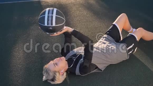 金发美女躺在地上打篮球用耳机听音乐美女视频的预览图