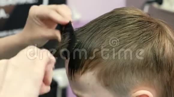 巴伯他的手梳和剪金发短男孩他的头发砰砰地用剪刀变薄视频的预览图