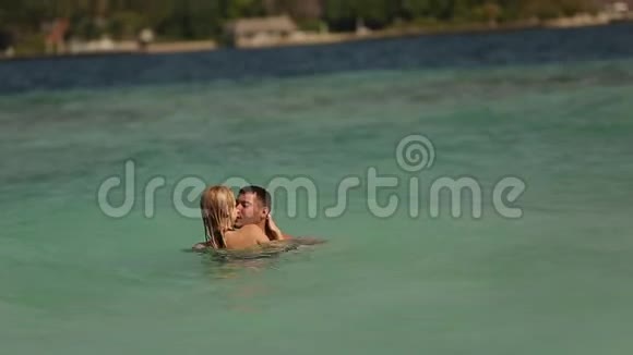 可爱的一对夫妇在印度洋的空海滩上游泳两位恋人在蜜月时用蓝色洗澡和接吻的录像视频的预览图