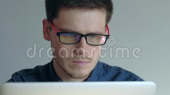 戴眼镜的人在白色背景的笔记本电脑上工作视频的预览图