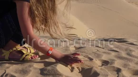 在炎热的撒哈拉沙漠中少女手拿着沙子倒着沙子特写手视频的预览图