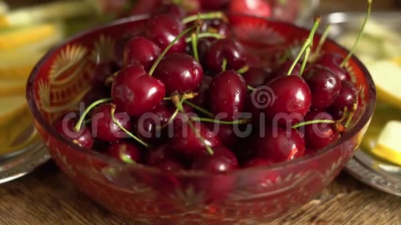 新鲜的夏季水果老式水晶碗樱桃在旧木桌上视频的预览图
