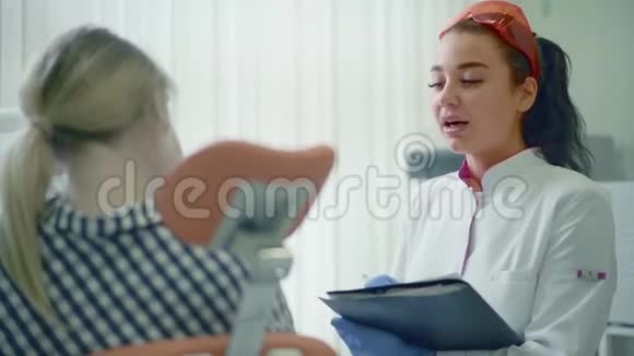 带剪贴板的女牙医和牙科诊所的女病人视频的预览图