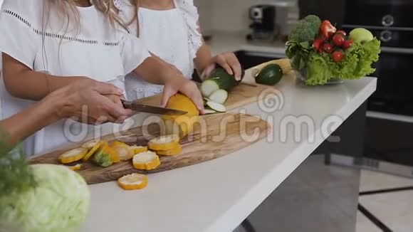 女手用刀切西葫芦深绿色和黄色的西葫芦放在厨房的切割板上视频的预览图
