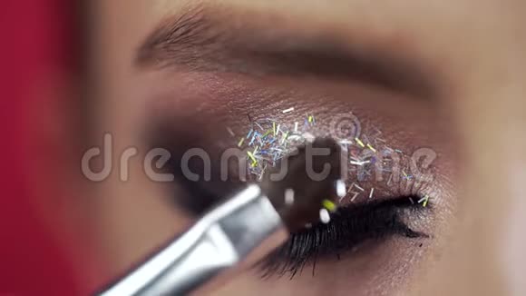 在女人的眼皮涂上闪光剂做晚间化妆眼睛化妆化妆师的工作特写视频的预览图