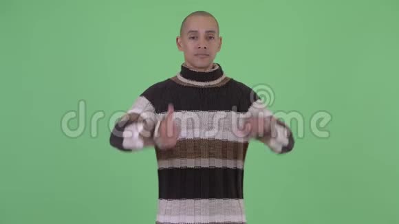 困惑的秃头多民族男人在竖起大拇指和竖起大拇指之间做出选择视频的预览图