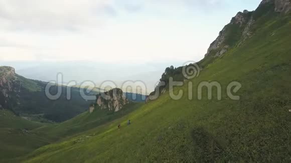 徒步旅行者背着背包从飞行无人机爬到绿色的山景视频的预览图