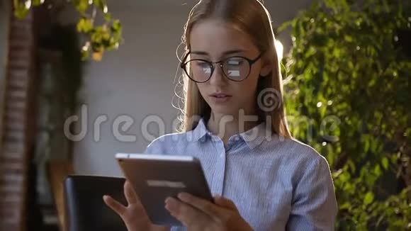 办公室里戴眼镜和平板电脑一起工作的女商人很累使用无线网络的白人年轻女学生肖像视频的预览图