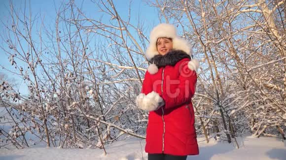 幸福的女孩在森林里日落时双手举起雪雪在阳光下落下闪闪发光冬天孩子们玩视频的预览图