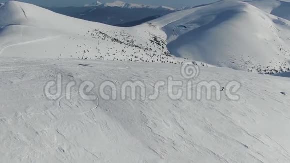 一个人在山上的斜坡上快速滑行令人惊叹的雪山景色空中射击视频的预览图