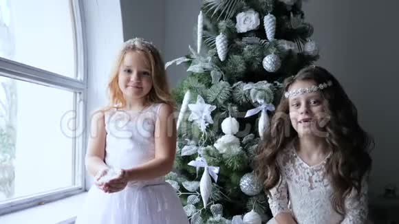 新年的气氛小女孩在圣诞树旁的冬照上玩人工雪视频的预览图