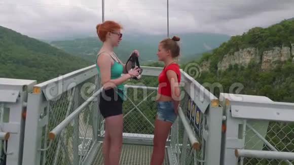 红发白种人的姐姐戴着虚拟现实眼镜戴在年轻的金发女郎身上背景是山谷视频的预览图