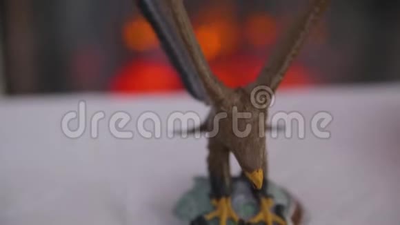 在模糊的壁炉上悬挂着两个金色结婚戒指的鹰的特写木制雕像视频的预览图