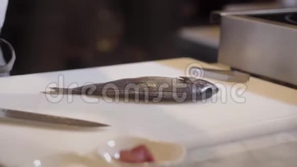 厨师手在橡胶手套准备生鱼超过切割板手控制鱼片与骨头的分离食物视频的预览图