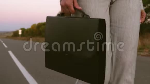 女商人手里拿着黑色的公文包穿着裤子穿着沥青上的夹克关上了门视频的预览图