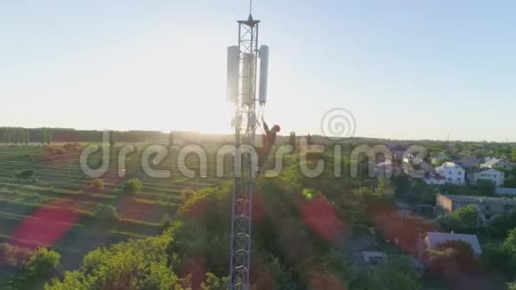 天线通信塔上的高空工作人员打移动电话在阳光下显示拇指无人机视图视频的预览图
