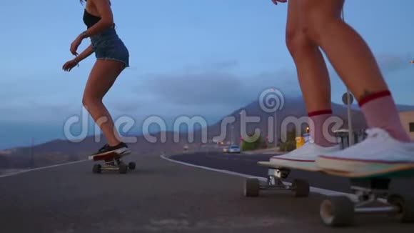 接近一个滑板和两个女孩谁骑在木板从一个山的背景岩石和天空慢慢视频的预览图