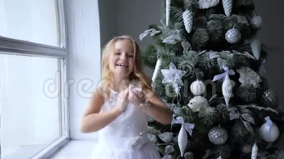 小女孩在圣诞气氛中在装饰好的圣诞树附近玩人工雪视频的预览图