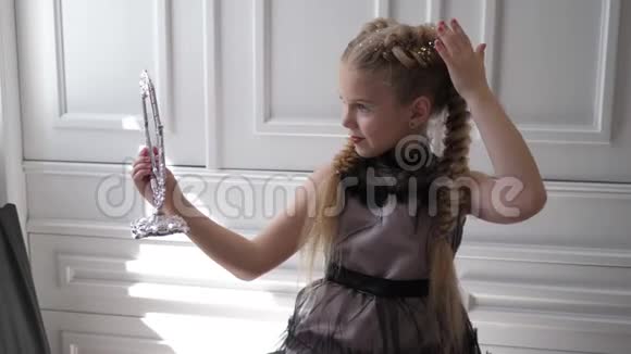 时尚的小女孩漂亮的发型和时尚的化妆在背景白墙上照镜子视频的预览图