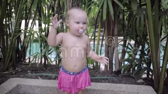 可爱的女孩一岁有个假人站在户外淋浴下4k视频的预览图