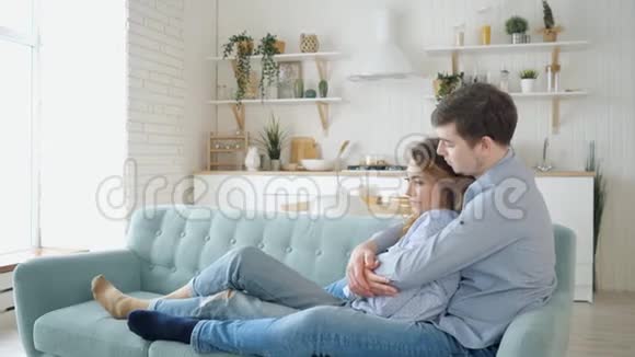 男人慢慢地拥抱坐在沙发上的女士在厨房里接吻视频的预览图