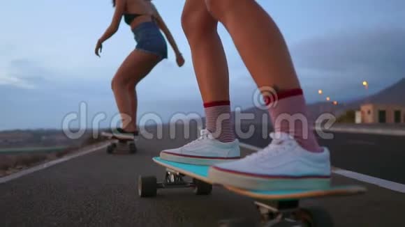 接近一个滑板和两个女孩谁骑在木板从一个山的背景岩石和天空慢慢视频的预览图