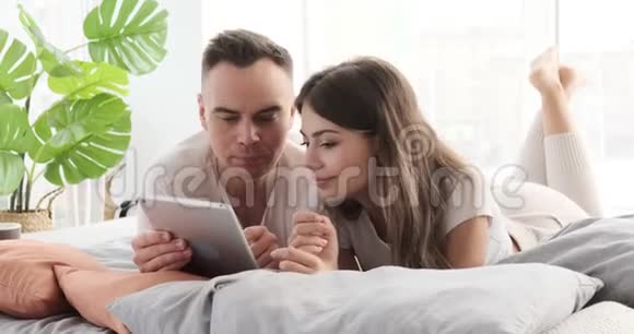 在床上使用数码平板电脑的情侣视频的预览图