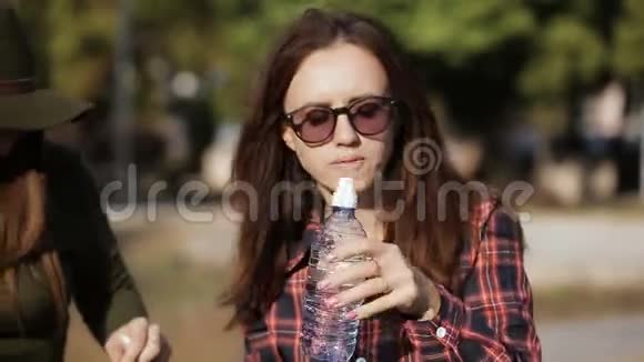 两个朋友在城市街头吃午餐三明治那个女孩从瓶子里喝水视频的预览图