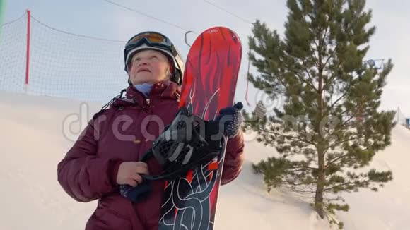 年长的女人站在山上拿着滑雪板视频的预览图