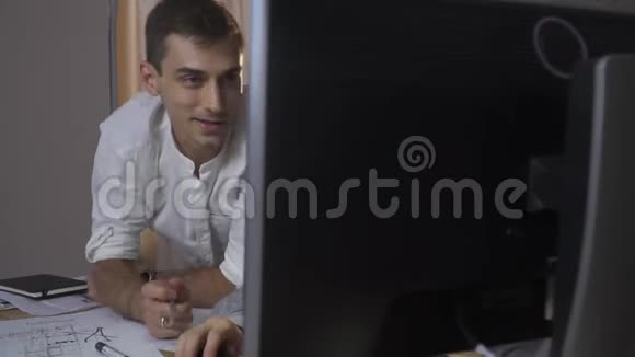 一个穿衬衫的人坐在电脑前用铅笔在显示器上指着两个人在加班视频的预览图