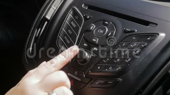 汽车多媒体系统中女性手调节无线电声级的慢动作特写镜头视频的预览图