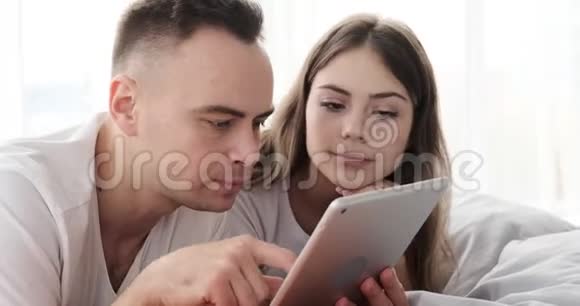 在床上使用数码平板电脑的情侣视频的预览图